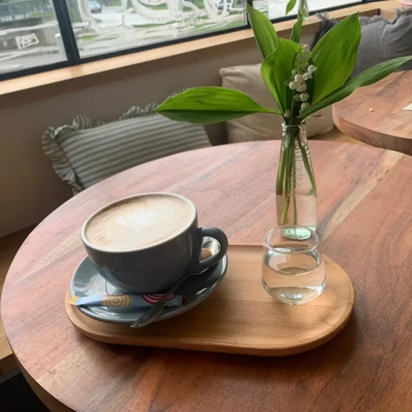 Vollmundiger, perfekter Cappuchino, dazu ein Gläschen Wasser neben frischen Blümchen
