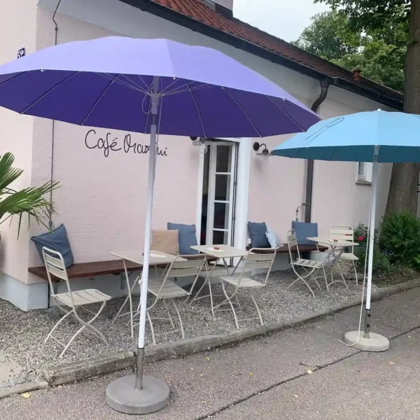Das Café mit Außenbereich hinten, schönen Pflanzen und bunten Sonnenschirmen