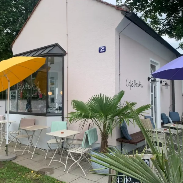 Das Café mit Außenbereich vorn, schönen Pflanzen und bunten Sonnenschirmen