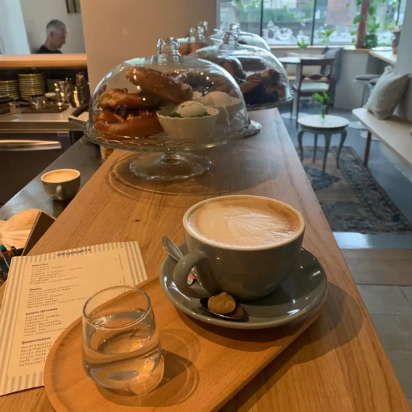 Frischer Cappuccino auf Theke mit Tablett und kleinem Wasser dazu