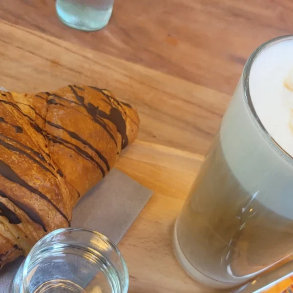 Süßes Frühstück mit Latte Macchiato und frisch gebackenem Schokoladencroissant